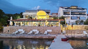 Hotel à beira-mar com paredes de pedra, área de estar externa e piscina.