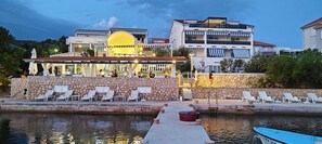 Ein Hotel am Wasserufer mit Steinmauern, Außenbereich und Pool.