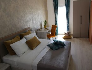 Ein Hotelzimmer mit einem Bett, einem kleinen Tisch, einem orangefarbenen Sessel und einem Kleiderschrank.