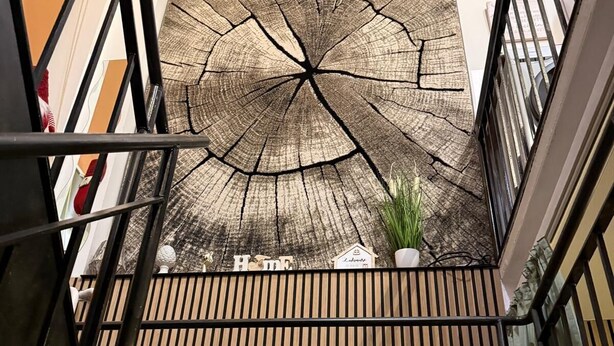 Una escalera con barandilla de madera y una gran obra de arte texturizada en la pared superior.