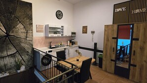 Una cocina compacta con comedor, una gran obra de arte con forma de anillo de árbol, un reloj y un letrero que dice 'Love Home'.