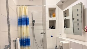 Un baño moderno con ducha, inodoro, lavamanos y espejo.
