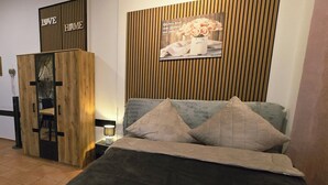 Un dormitorio con una cama, una mesita de noche, un armario de madera y un cartel en la pared.