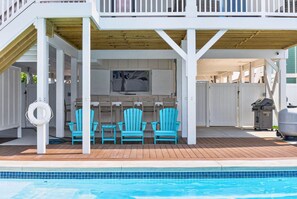 A covered outdoor area with a pool, wooden deck, and two blue Adirondack chairs. - Ultimate Luxury 7-bedroom, 7+bathroom w/private pool &elevator, steps from the beach (Holden Beach)