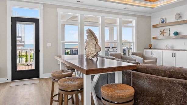 A modern interior with a wooden ceiling, a dining area with stools, a large window, and a view of the outdoors. - Ultimate Luxury 7-bedroom, 7+bathroom w/private pool &elevator, steps from the beach (Holden Beach)