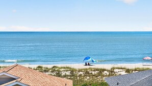 A beach view with a house, a blue umbrella, and a red umbrella on the sand. - Ultimate Luxury 7-bedroom, 7+bathroom w/private pool &elevator, steps from the beach (Holden Beach)