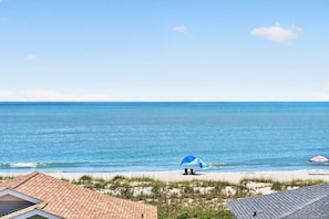 A beach view with a house, a blue umbrella, and a red umbrella on the sand. - Ultimate Luxury 7-bedroom, 7+bathroom w/private pool &elevator, steps from the beach (Holden Beach)