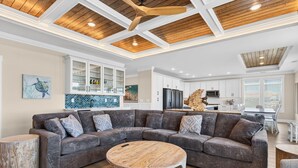 A modern living room with a sectional sofa, a round coffee table, and a wooden accent wall. - Ultimate Luxury 7-bedroom, 7+bathroom w/private pool &elevator, steps from the beach (Holden Beach)