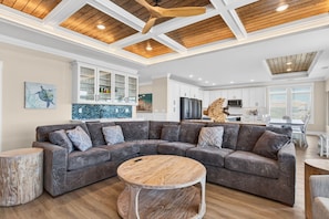 A modern living room with a sectional sofa, a round coffee table, and a wooden accent wall. - Ultimate Luxury 7-bedroom, 7+bathroom w/private pool &elevator, steps from the beach (Holden Beach)