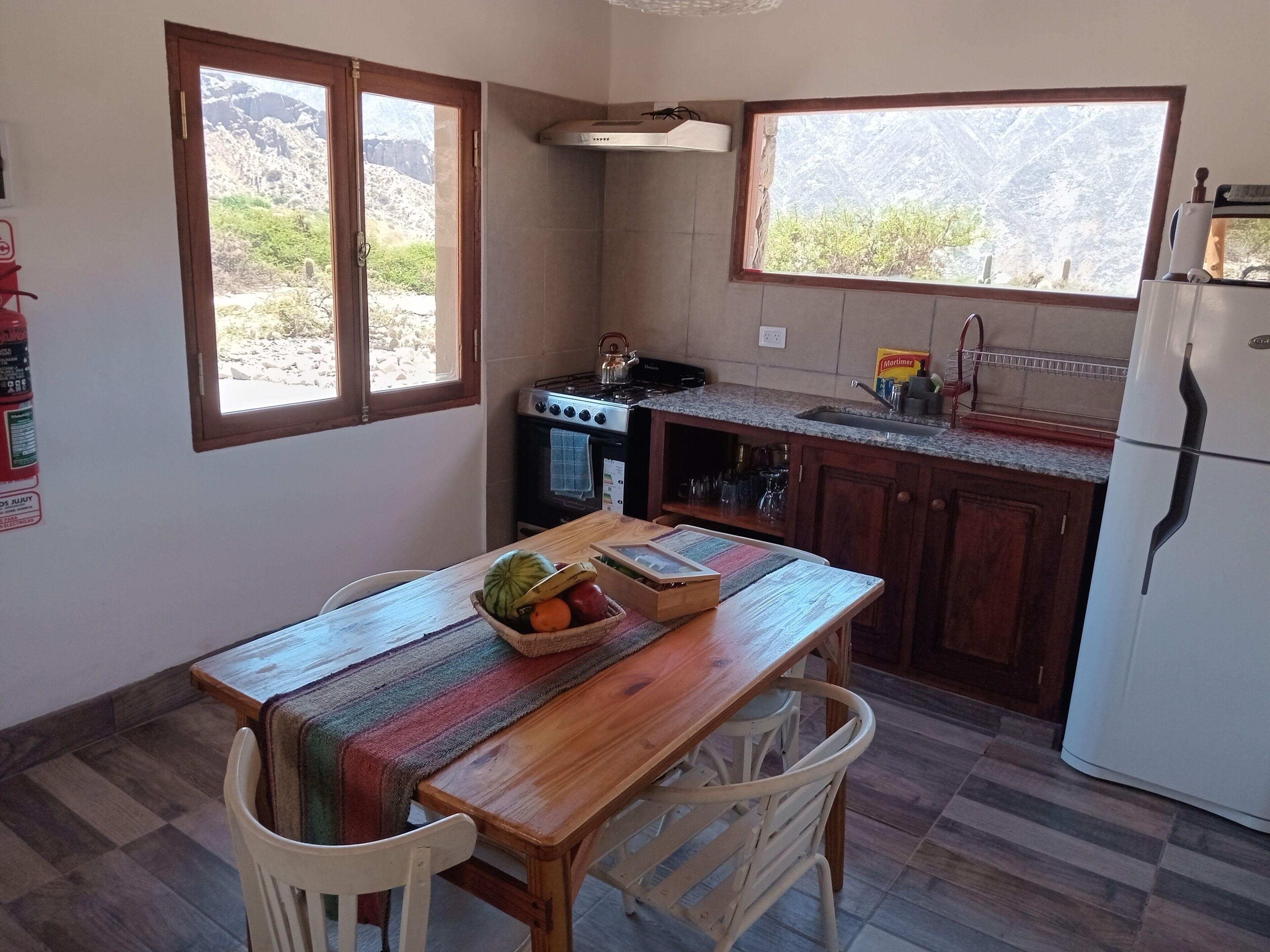 A kitchen with a wooden table, chairs, a stove, a sink, and a refrigerator.