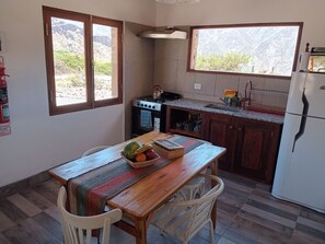 Une cuisine avec une table en bois, des chaises, une cuisinière, un évier et un réfrigérateur.