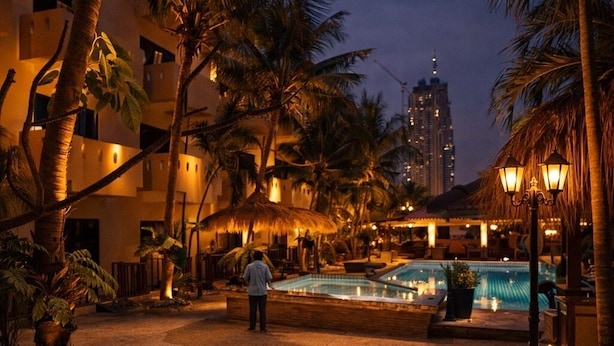 A nighttime resort pool area with palm trees, a pool, and a building in the background. - Akira Resort (Pattaya)