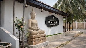 A Buddha statue in front of a building with a sign that reads "AKIRA RESORT". - Akira Resort (Pattaya)