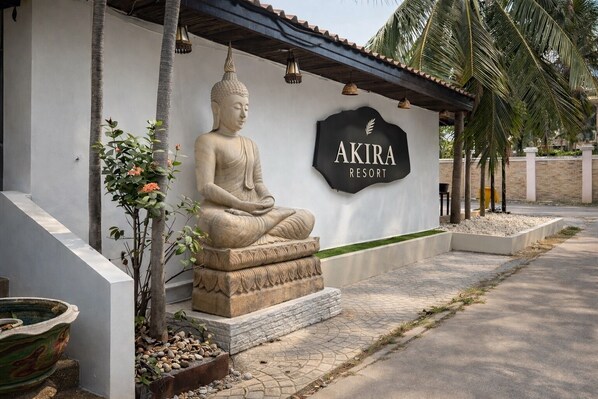 A Buddha statue in front of a building with a sign that reads "AKIRA RESORT". - Akira Resort (Pattaya)