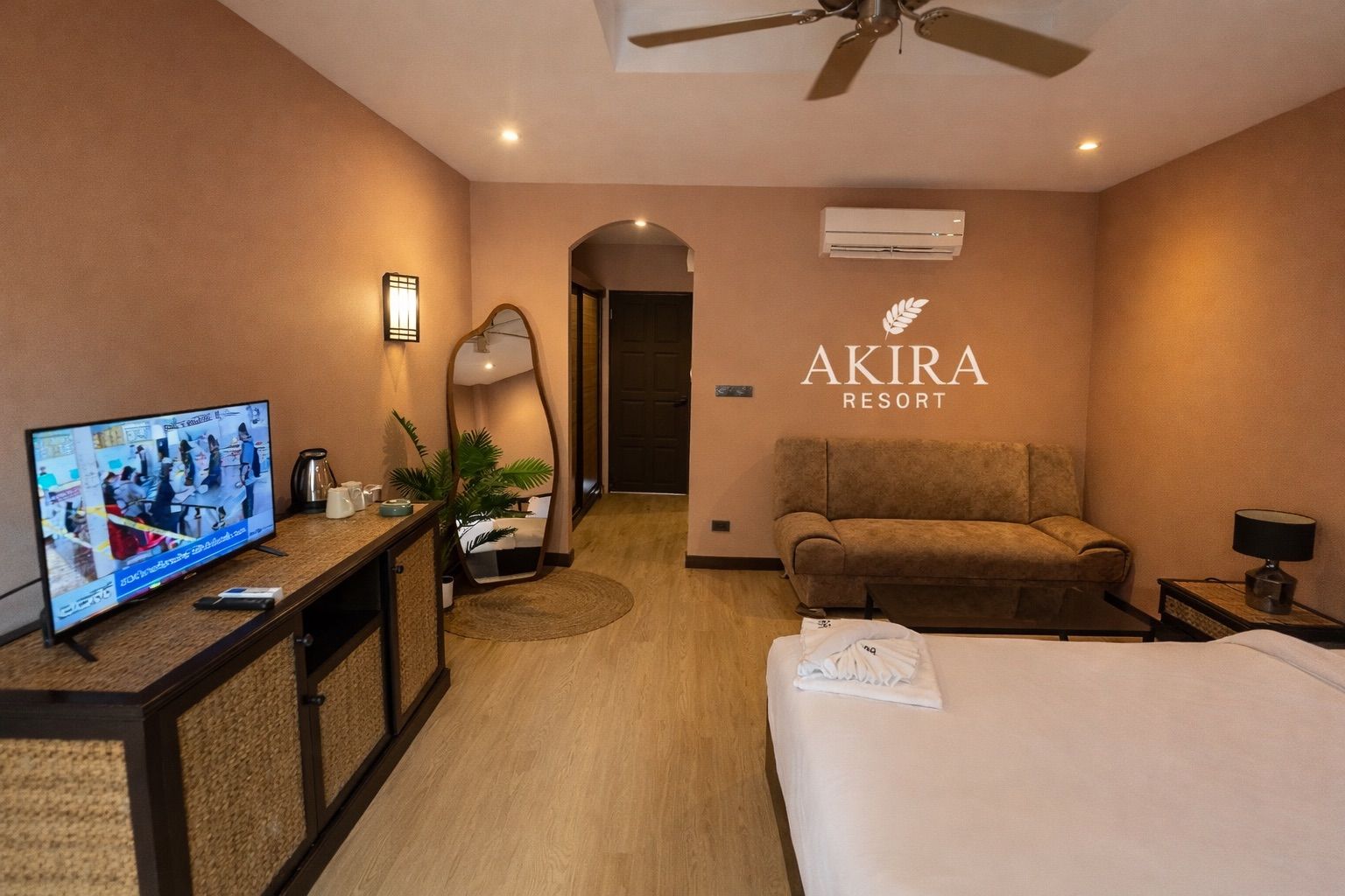 Una habitación de hotel con una cama, un sofá, un televisor, un escritorio y un espejo.