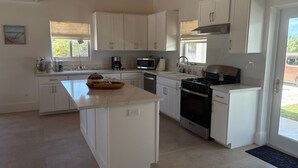 A modern kitchen with white cabinetry, a central island, a stove, and a microwave.