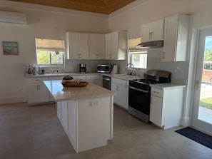 Une cuisine moderne avec des meubles blancs, un îlot central, une cuisinière et un four à micro-ondes.