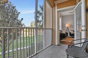 A balcony with a metal railing, a table, and a chair. - 3bd/2ba Elegant Condo With Resort Access (Kissimmee)