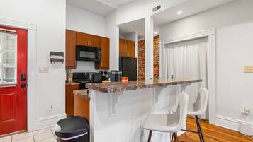 A compact kitchen with a central island, wooden cabinets, and a red door.