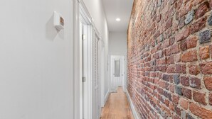 Un pasillo con una pared de ladrillo a un lado y puertas blancas al otro.