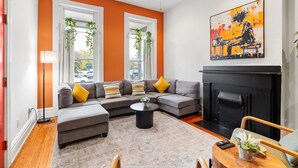 Una sala de estar con un sofá modular, una chimenea y un cuadro en la pared.