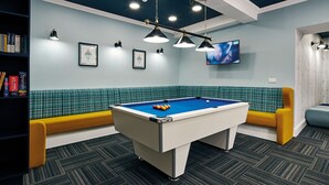 A pool table in a room with a blue and white color scheme, a bookshelf, and a television on the wall. - Ty Willis House (Bangor)