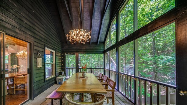 A wooden deck with a dining table and chairs, large windows, and a chandelier. - Heavenly Mountain Escape in Big Canoe! Golf & Lake (Jasper)
