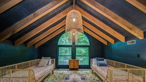 A cozy attic bedroom with two wooden bunk beds, a large window with a view of trees, and a hanging light fixture. - Heavenly Mountain Escape in Big Canoe! Golf & Lake (Jasper)
