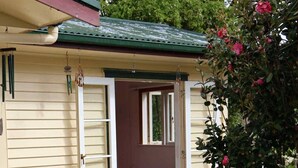 Ein kleines Haus mit einer Veranda, zwei weißen Stühlen und einem Tisch.
