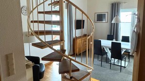 Una scala a chiocciola conduce a una sala da pranzo con tavolo e sedie.
