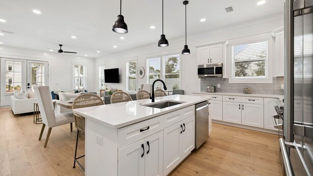 A modern kitchen with white cabinetry, a central island, and pendant lighting. - Modern Pet-Friendly Retreat for Families w/2 Bunk Rooms | Brand New Pool! (Seagrove Beach)