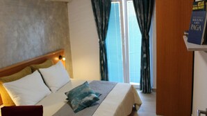 A hotel room with a bed, a wooden headboard, a nightstand, a red chair, a window with curtains, and a door. - Adriatic Apartment With Large Terrace (Novalja)