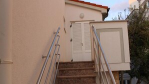 A set of stone steps with metal railings leading to a white door with shutters. - Adriatic Apartment With Large Terrace (Novalja)