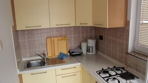 A compact kitchen with a sink, stove, and cabinets. - Adriatic Apartment With Large Terrace (Novalja)