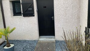 Un edificio con facciata strutturata, una porta in legno scuro e una piccola finestra con persiane.