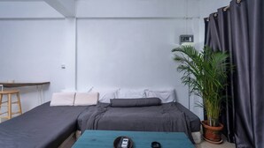Ein kleiner, moderner Raum mit einem Bett, einem Schreibtisch und einer Topfpflanze.