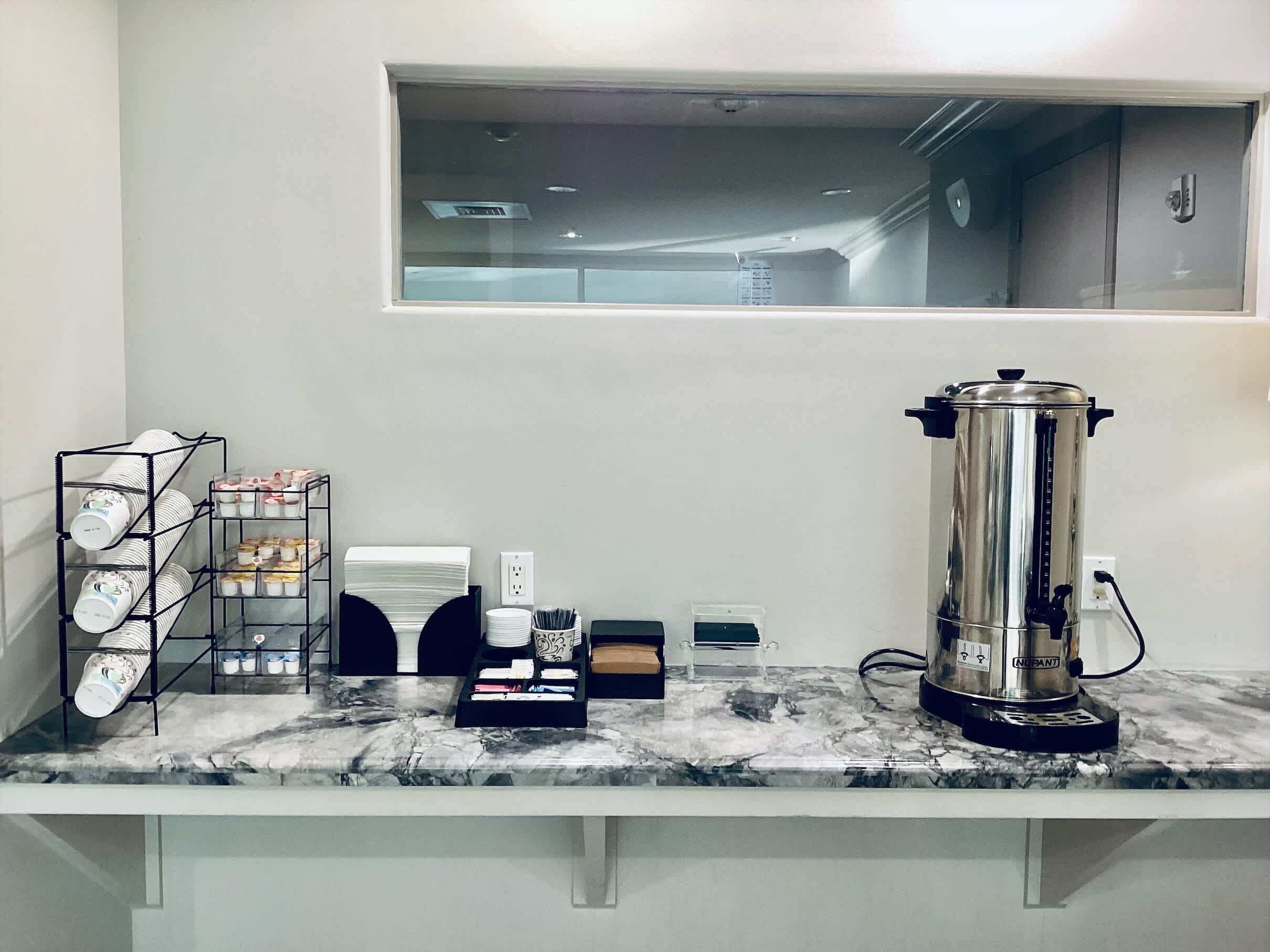 A kitchen counter with a coffee maker, a dish rack, and a window above.