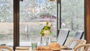 Ett runt bord med stolar, en vas med blommor, ett glas och en fralla.