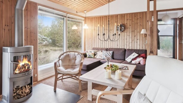 Ett mysigt vardagsrum med en vedeldad kamin, en soffa, ett bord och en stol.
