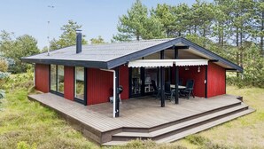 Ett modernt hus med en veranda, stora fönster och en täckt uteplats.