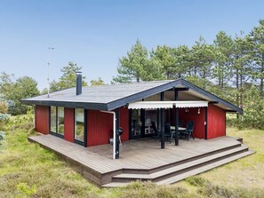 Moderni talo, jossa on terassi, suuret ikkunat ja katettu ulkotila oleskelua varten.