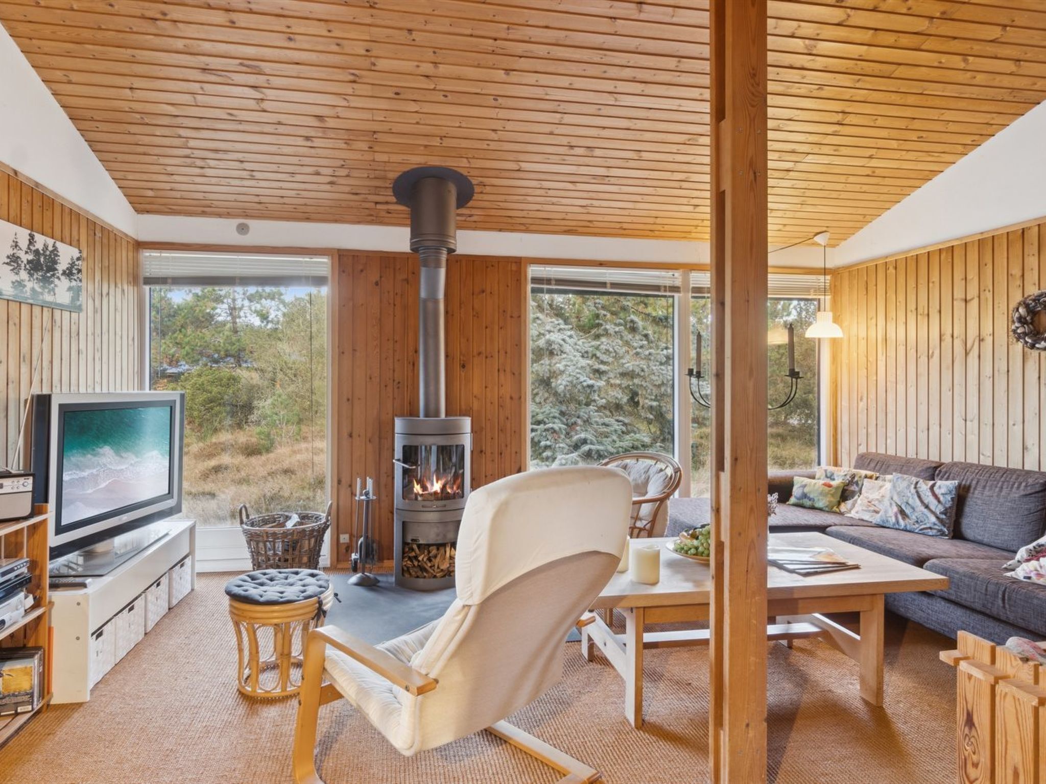 A cozy living room with a fireplace, a television, a comfortable chair, a sofa, and a dining table.