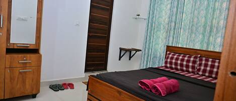 A bedroom with a wooden bed, a wardrobe, a mirror, and a door.