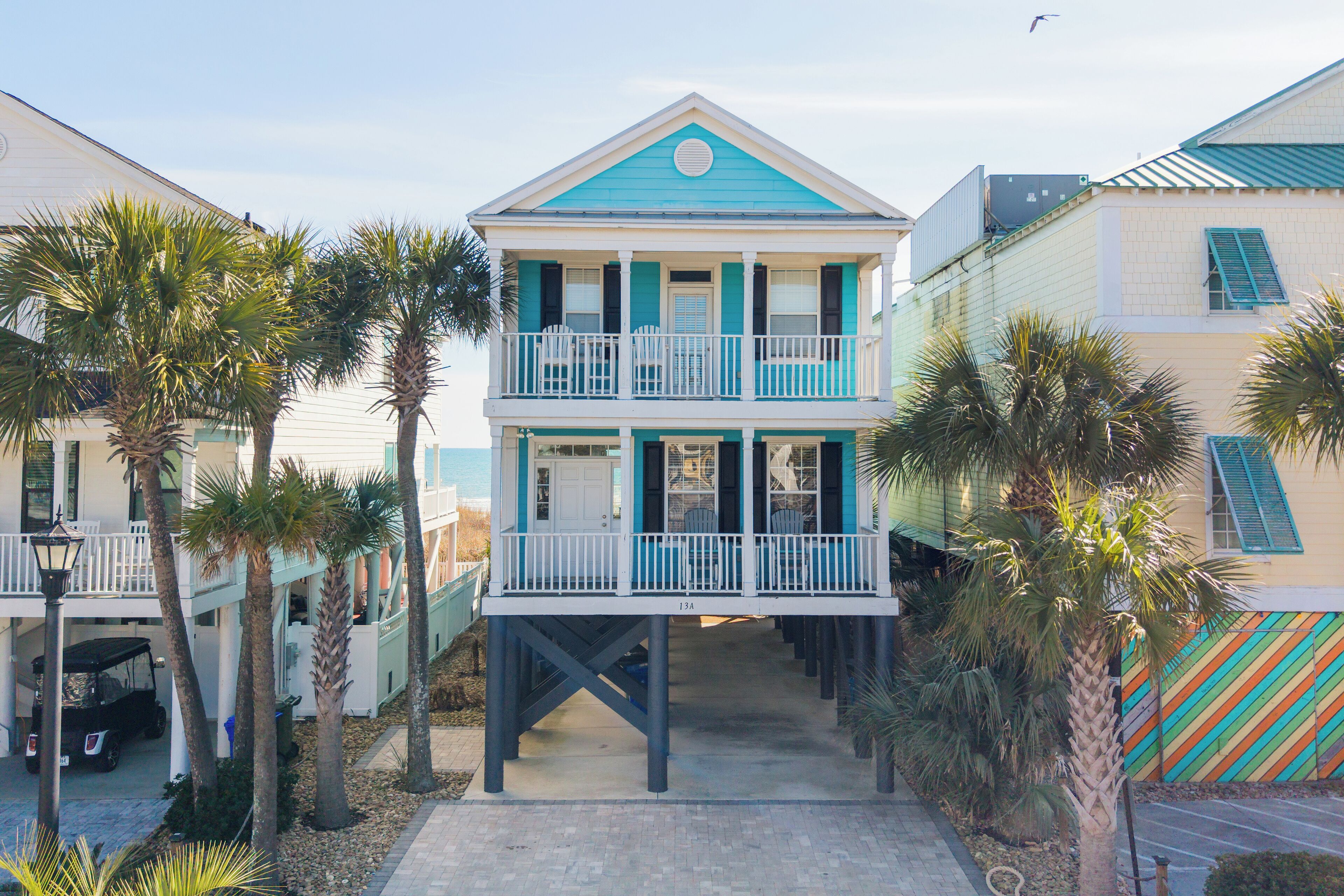 A two-story building with a balcony on the upper level, surrounded by palm trees.