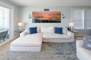 A living room with a large painting, two side tables with lamps, a white sofa, and a patterned rug. - Oceanfront 5 Bedroom House Next To the Surfside Beach Pier! - Pier Pleasure (Surfside Beach)
