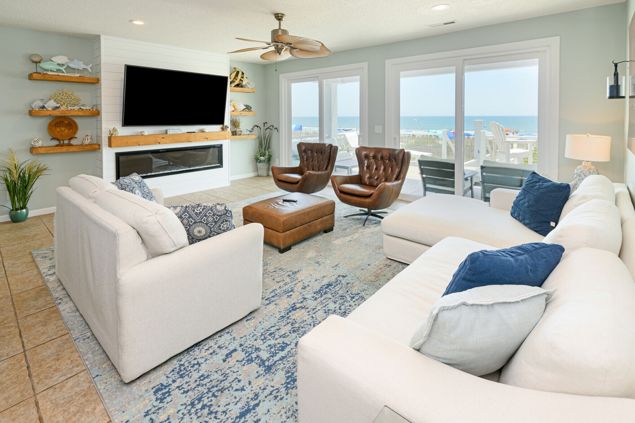 A living room with a fireplace, white sofas, a coffee table, and a TV mounted on the wall.