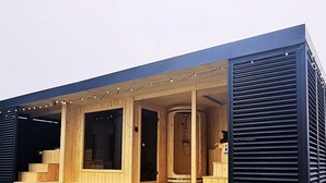 Eine moderne Sauna mit Holzwänden und Glastür, ausgestattet mit einer Bank und einem Duschbereich.