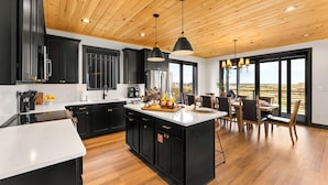 Una cocina moderna con armarios negros, techo de madera y un comedor con vistas.
