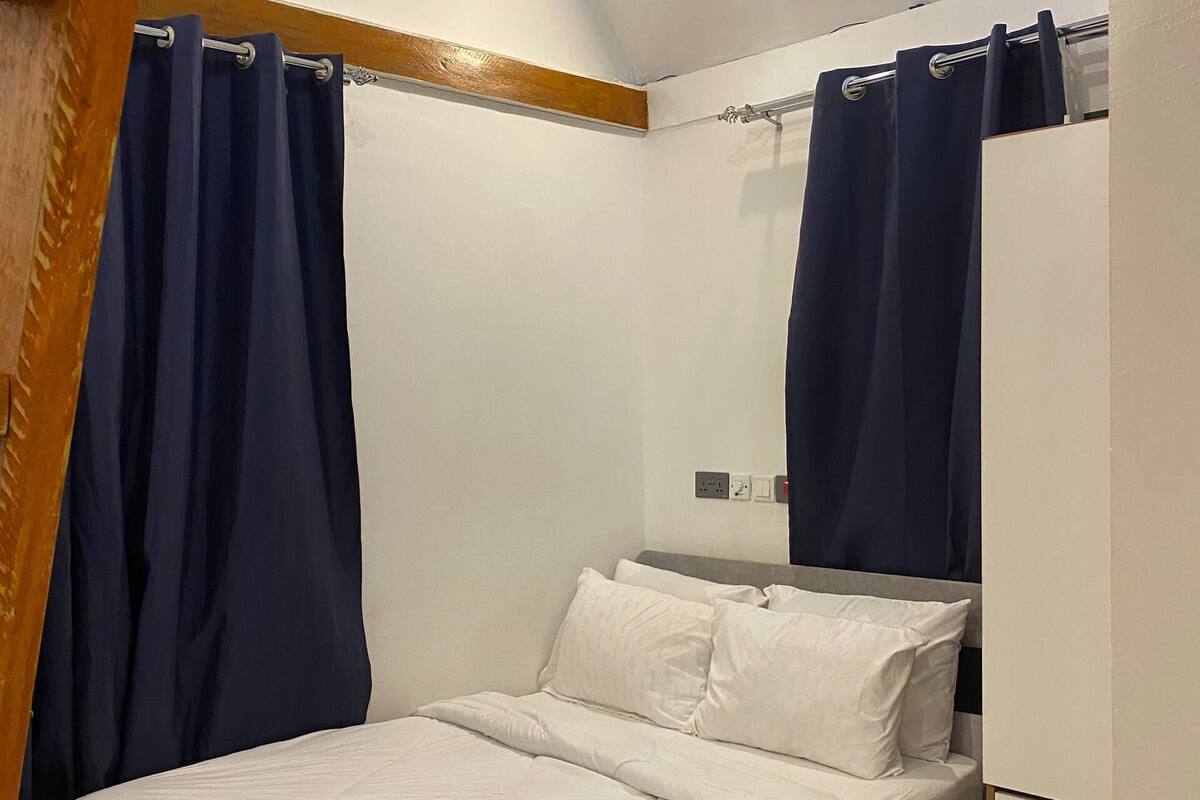 Un dormitorio con cama, ropa de cama blanca, cabecera de madera y mesita de noche.