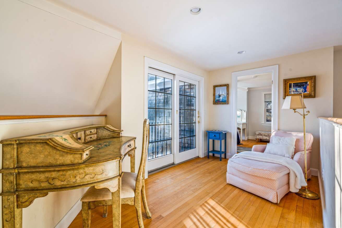 A room with a wooden floor, a piano, a bed, a chair, and a lamp.